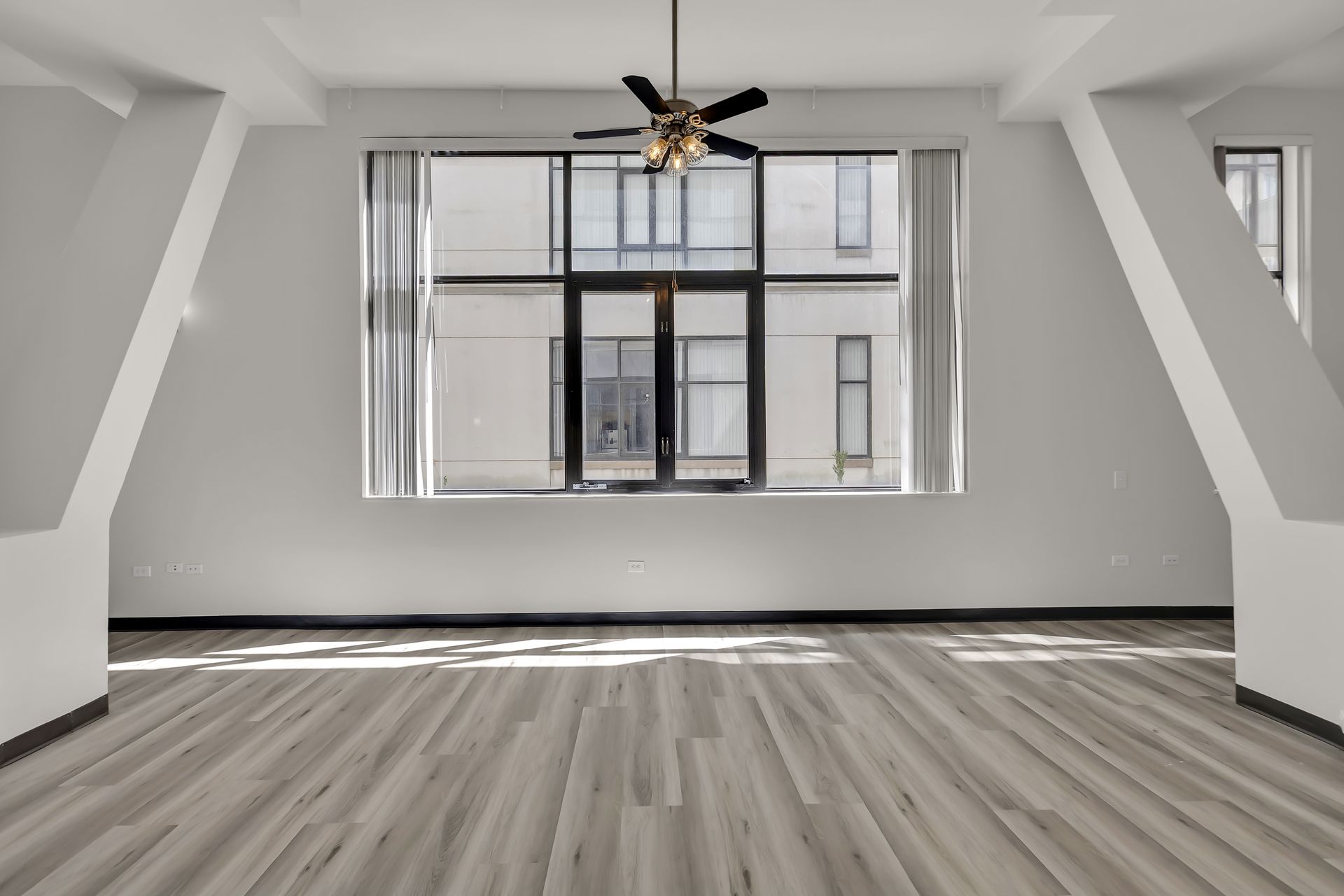 Loft 207 living area with a large window and ceiling fan, 1900 Elm Lofts