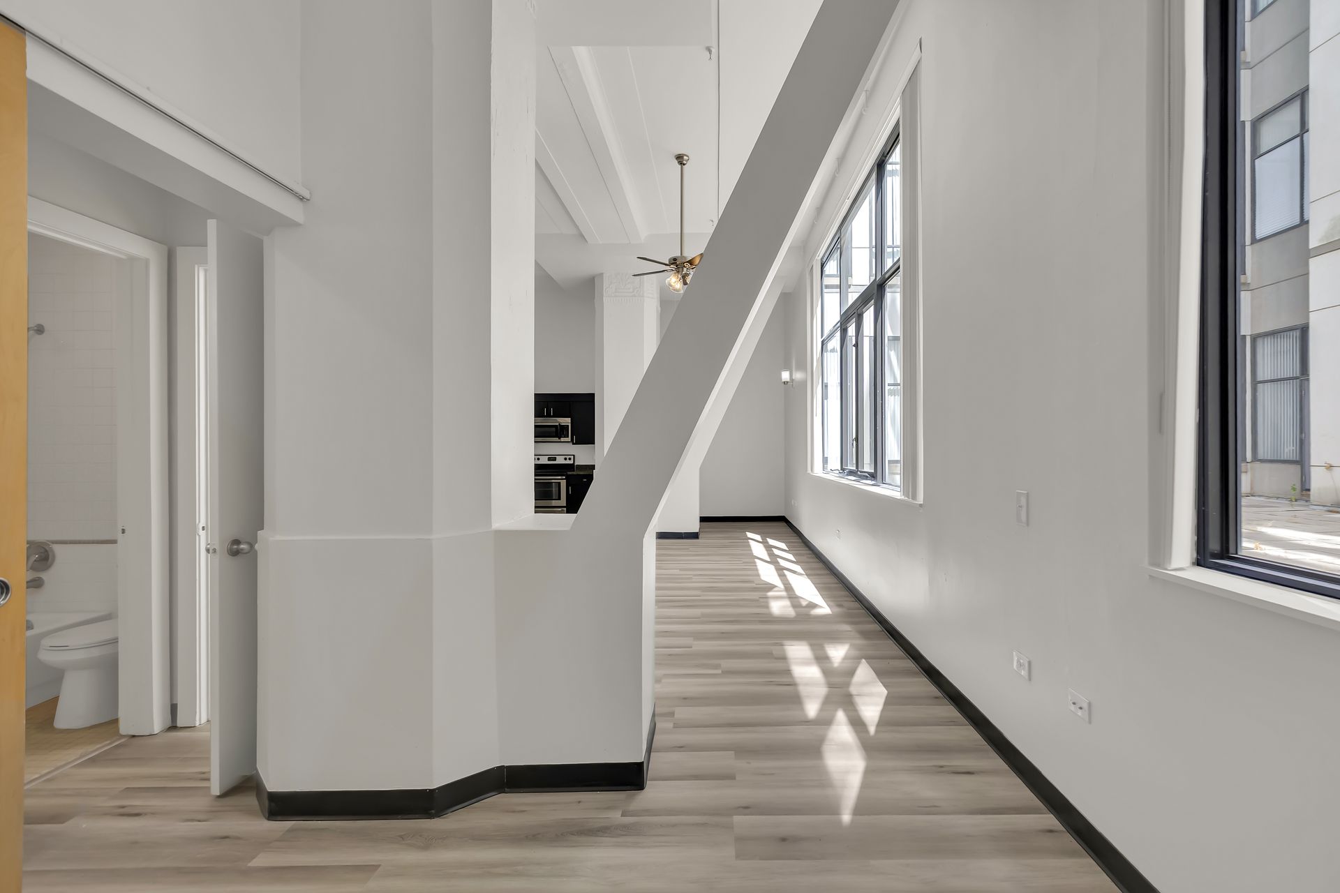 Loft living area with original column and tall window, 1900 Elm Lofts