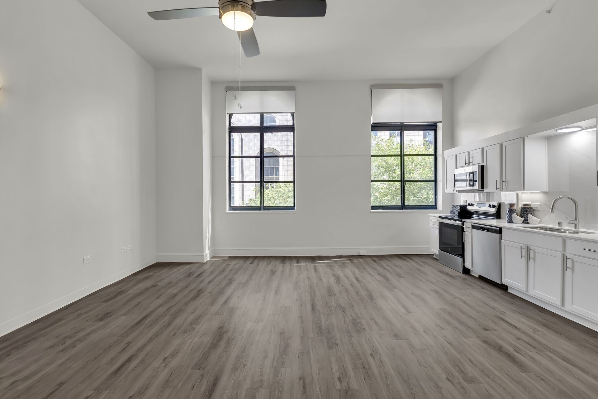 Loft 214 with two tall windows and wood-look floors, 1900 Elm Lofts